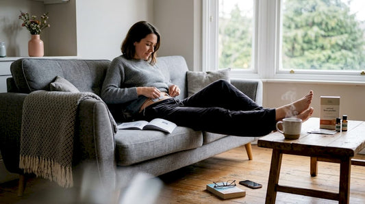 En kvinna sätter fast en TENS-apparat på magen hemma i sitt vardagsrum.